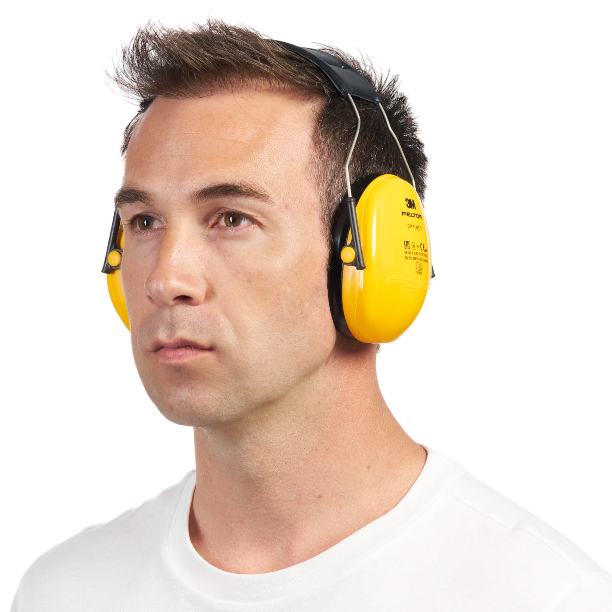 Ein Mann im weißen Hemd trägt 3M™ PELTOR™ Optime™ I Kapselgehörschutz H510A (SNR 27 dB, gelb) von 3M Deutschland GmbH und schaut mit neutralem Gesichtsausdruck vor weißem Hintergrund nach vorne.