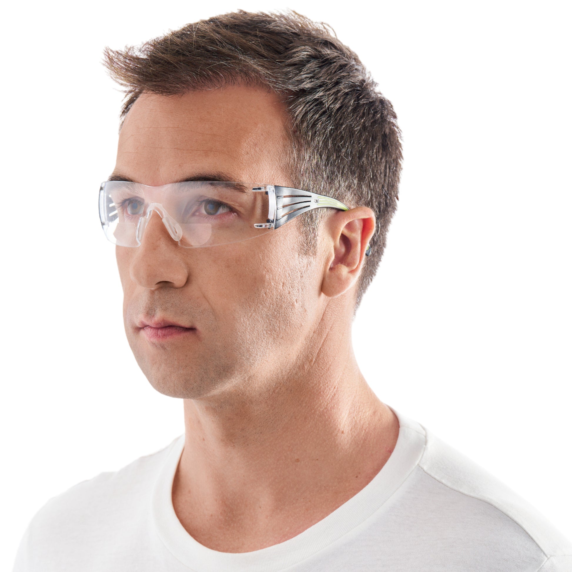 Eine Person mit kurzen braunen Haaren trägt eine 3M™ SecureFit™ Lese-Schutzbrille von 3M Deutschland GmbH und ein schlichtes weißes T-Shirt und blickt leicht zur Seite vor einem weißen Hintergrund.