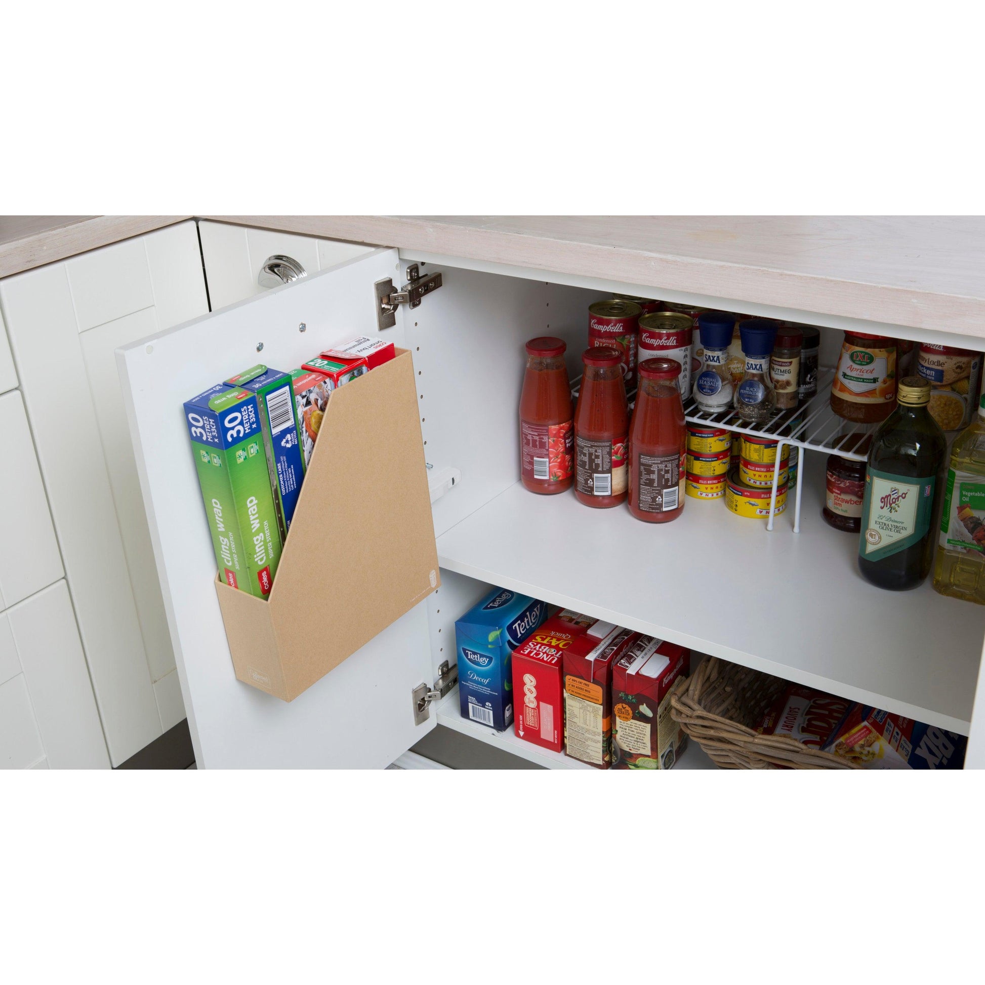 Ein Küchenschrank mit geöffneter Tür zeigt drei Müslischachteln in einer Halterung, die mit 3M Deutschland GmbH Scotch-FIX™ Doppelseitiges Innenmontageband an der Tür befestigt ist. Im Inneren befinden sich Gläser, Konserven, Flaschen und ein Korb auf dem unteren Regalboden.