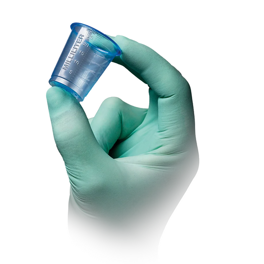 Eine hellgrün behandschuhte Hand hält einen der AMPri PP Medizinbecher 30 ml graduiert in transparentem Blau der AMPri Handelsgesellschaft mbH mit Milliliter-Graduierung auf weißem Hintergrund.