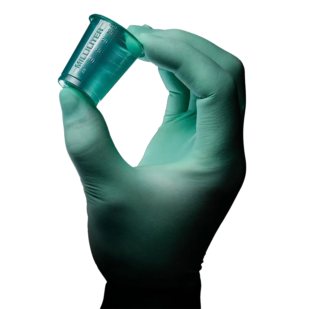 Eine behandschuhte Hand hält einen kleinen, durchscheinend grünen AMPri PP Medizinbecher mit geprägten Markierungen. Der weiße Hintergrund hebt die Hand und den Becher hervor, der von der AMPri Handelsgesellschaft mbH aus langlebigem Polypropylen hergestellt wird.
