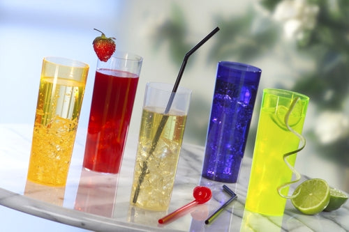 Fünf leuchtende Getränke in transparenten Starpak 0,3 l Longdrink-Gläsern stehen auf einer runden Marmorplatte, jedes in einer anderen Farbe und mit einer anderen Garnierung - Erdbeere, Limettenscheiben, spiralförmige Schale - und zwei Strohhalmen auf dem Tisch.