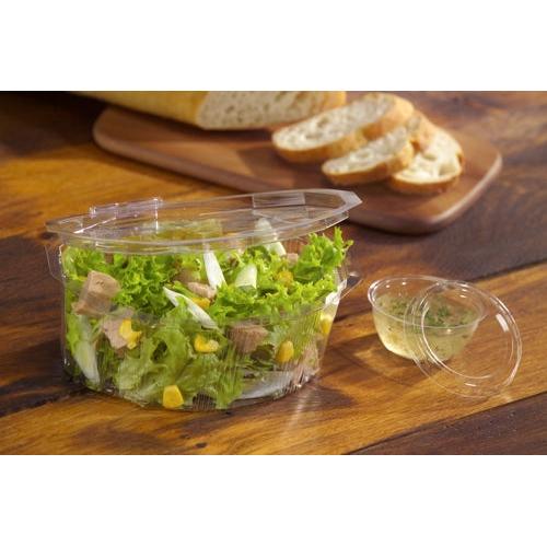 Ein klarer, runder Starpak 100 Deckel (PS, Ø 6,7 cm, 1 cm hoch) verschließt einen Plastikbehälter mit grünem Salat, Mais und Fleisch, im Hintergrund liegt auf einem Holzbrett geschnittenes Baguette.