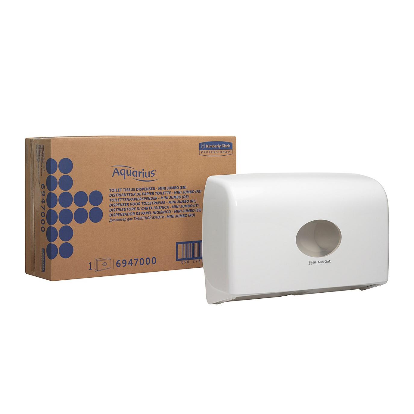 Ein weißer Aquarius™ Doppelrollen-Spender für Jumbo-Toilettenpapier Mini von Kimberly-Clark GmbH ist an der Wand neben einer braunen Schachtel mit der Aufschrift "Aquarius" und blauer Punktgrafik und Produktinformation angebracht.
