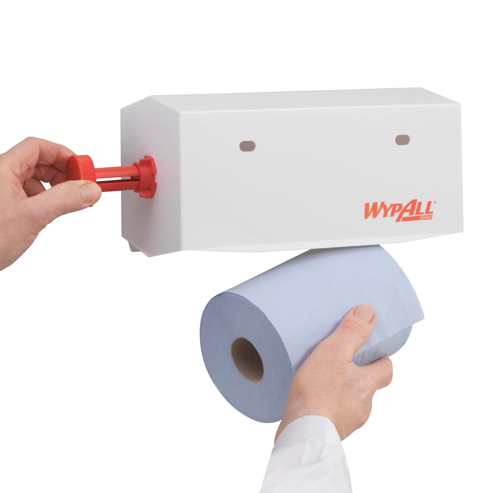 Jemand lädt eine blaue Papierhandtuchrolle in einen weißen Kimberly-Clark GmbH WypAll® Wischtuch-Spender - Kleinrollen (25 cm), wobei er die Rolle mit einer Hand hält und mit der anderen ein rotes Teil des Spenders einstellt.