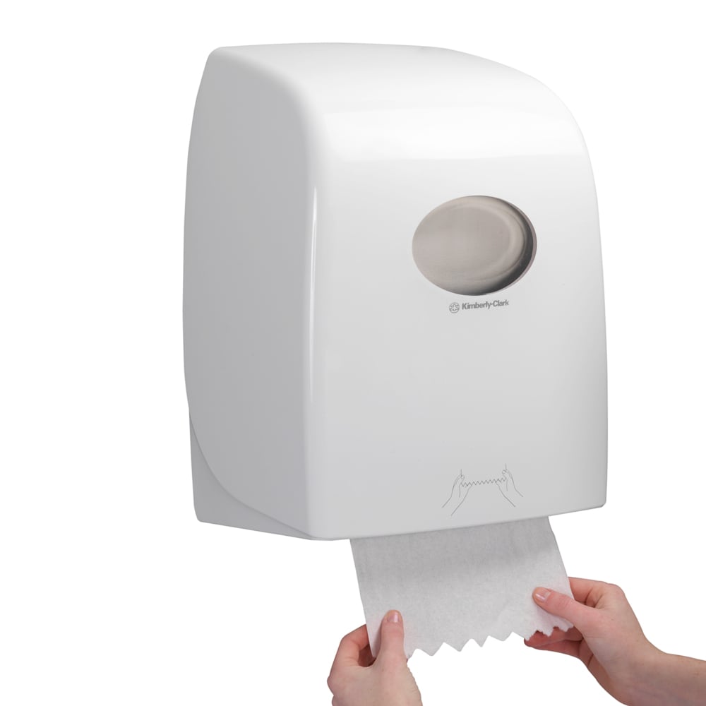 Jemand zieht ein Blatt Scott® ESSENTIAL™ Handtücher - Rolle aus einem weißen, an der Wand montierten Spender der Kimberly-Clark GmbH, dessen durchsichtiges Fenster den Blick auf die Handtuchrollen im Inneren freigibt.