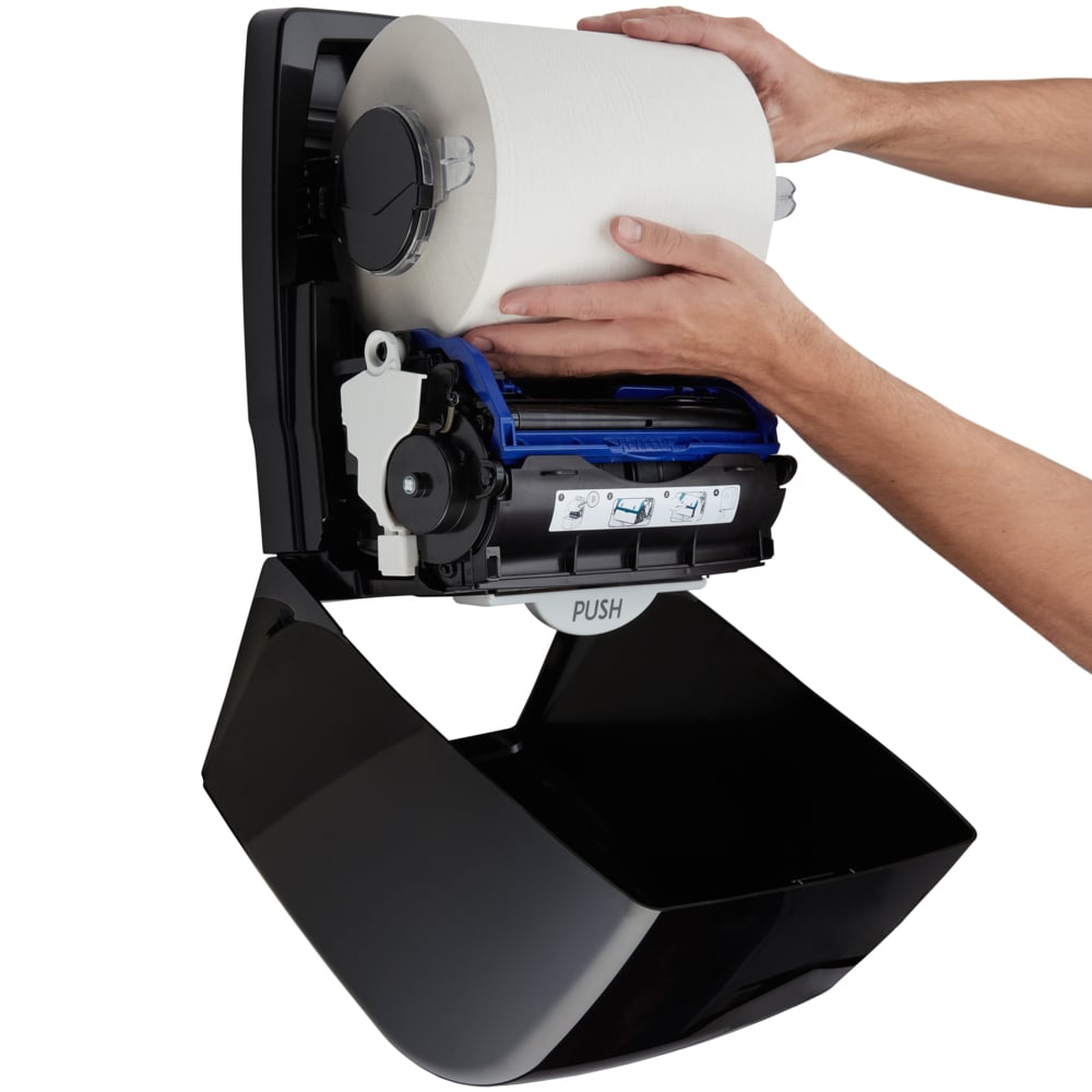 Eine Person lädt eine große Papierhandtuchrolle in den geöffneten Aquarius™ Rollenhandtuchspender (Schwarz, 38,20 x 30,90 x 24,00 cm) der Kimberly-Clark GmbH und sorgt so für eine hygienische Nutzung im professionellen Umfeld.