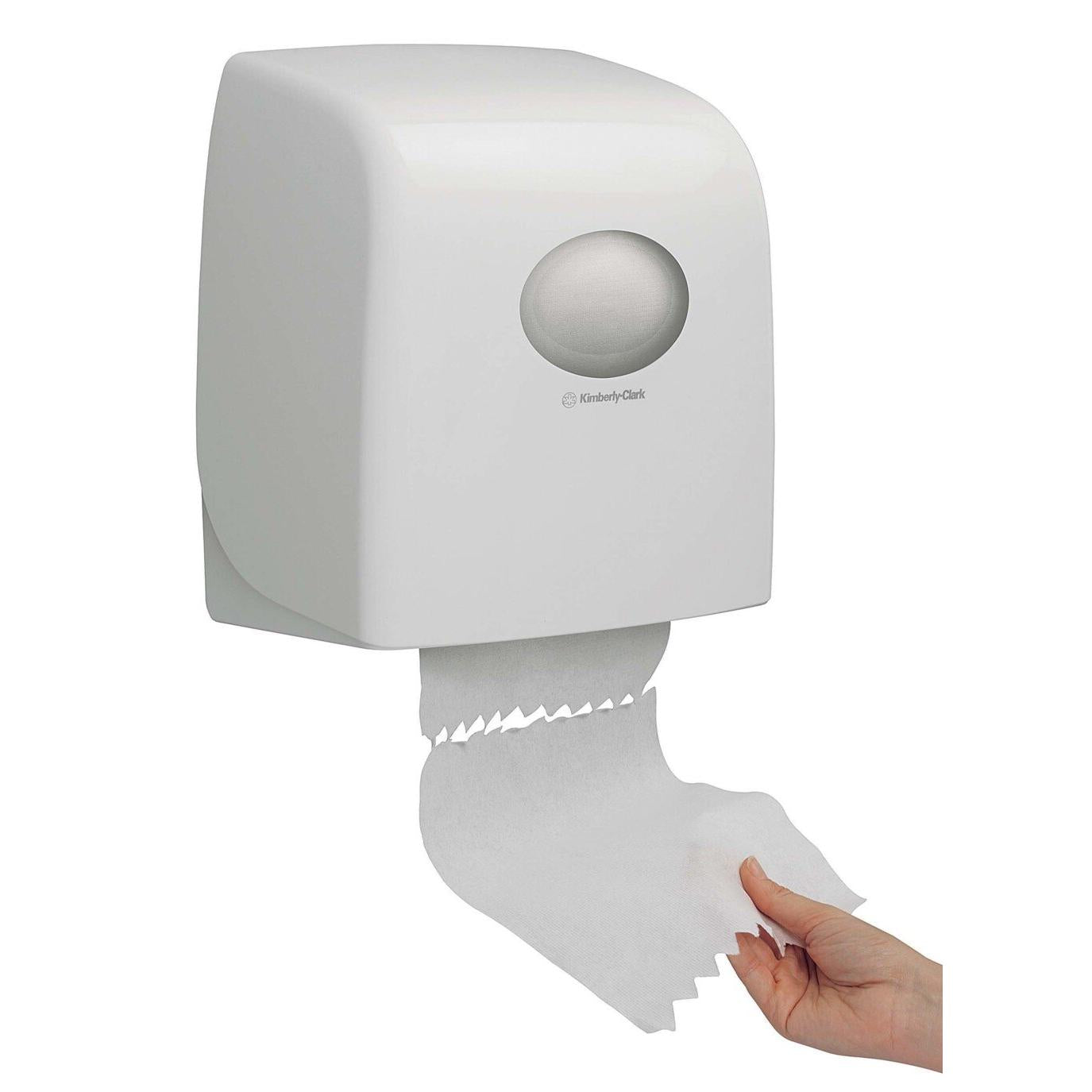 Eine Hand spendet Papierhandtücher aus einem weißen, an der Wand montierten Aquarius™ Slimroll™ Rollenhandtuchspender der Kimberly-Clark GmbH, der eine sichtbare Rolle im Inneren hat.