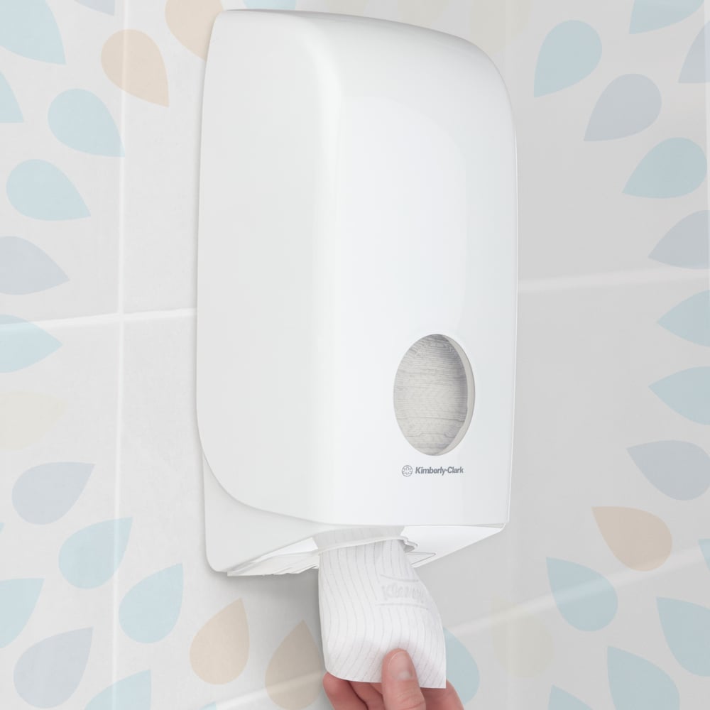 Eine Hand zieht ein Blatt aus einem an der Wand montierten Kleenex® Toilettenpapier Einzelblattsytem (Kimberly-Clark GmbH), Weiß, 200 Blatt pro Packung, 36 Packungen, in einem Badezimmer mit gemusterten Kachelwänden.