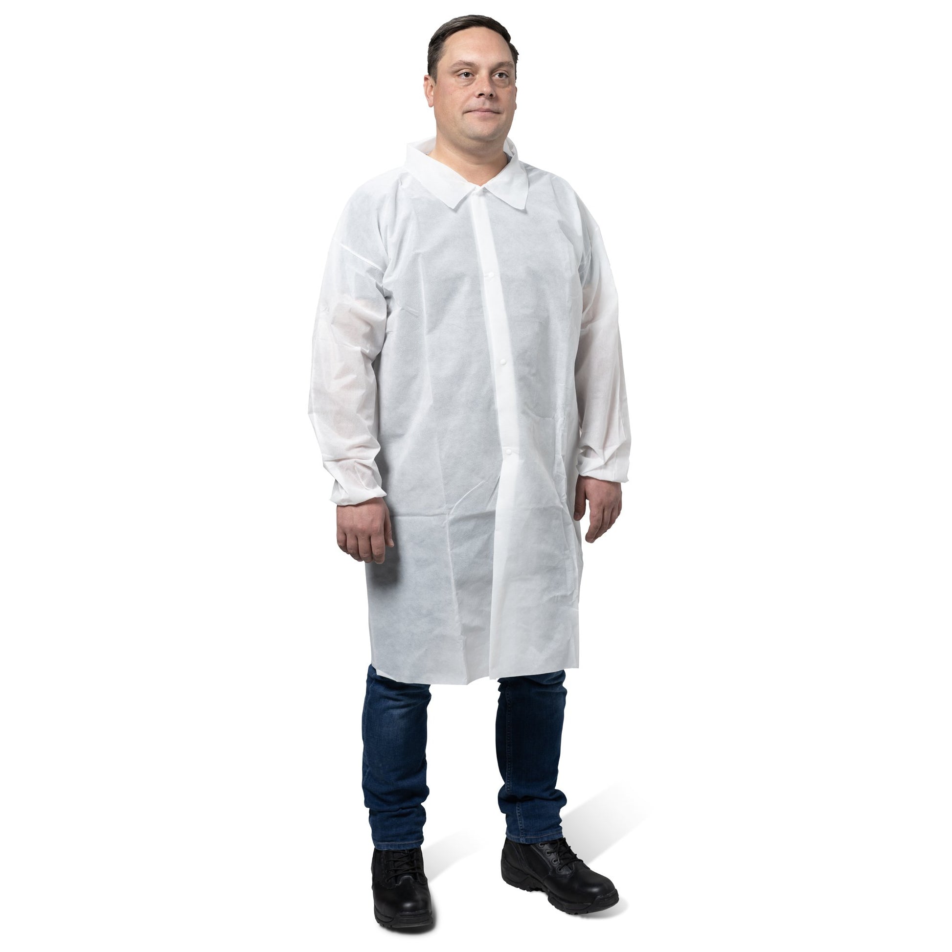 Ein Mann trägt einen weißen KleenGuard® KGA10 Leichter Schutzkittel für Besucher von Kimberly-Clark GmbH über einem Hemd mit Kragen, Jeans und schwarzen Schuhen und steht vor einem schlichten weißen Hintergrund.