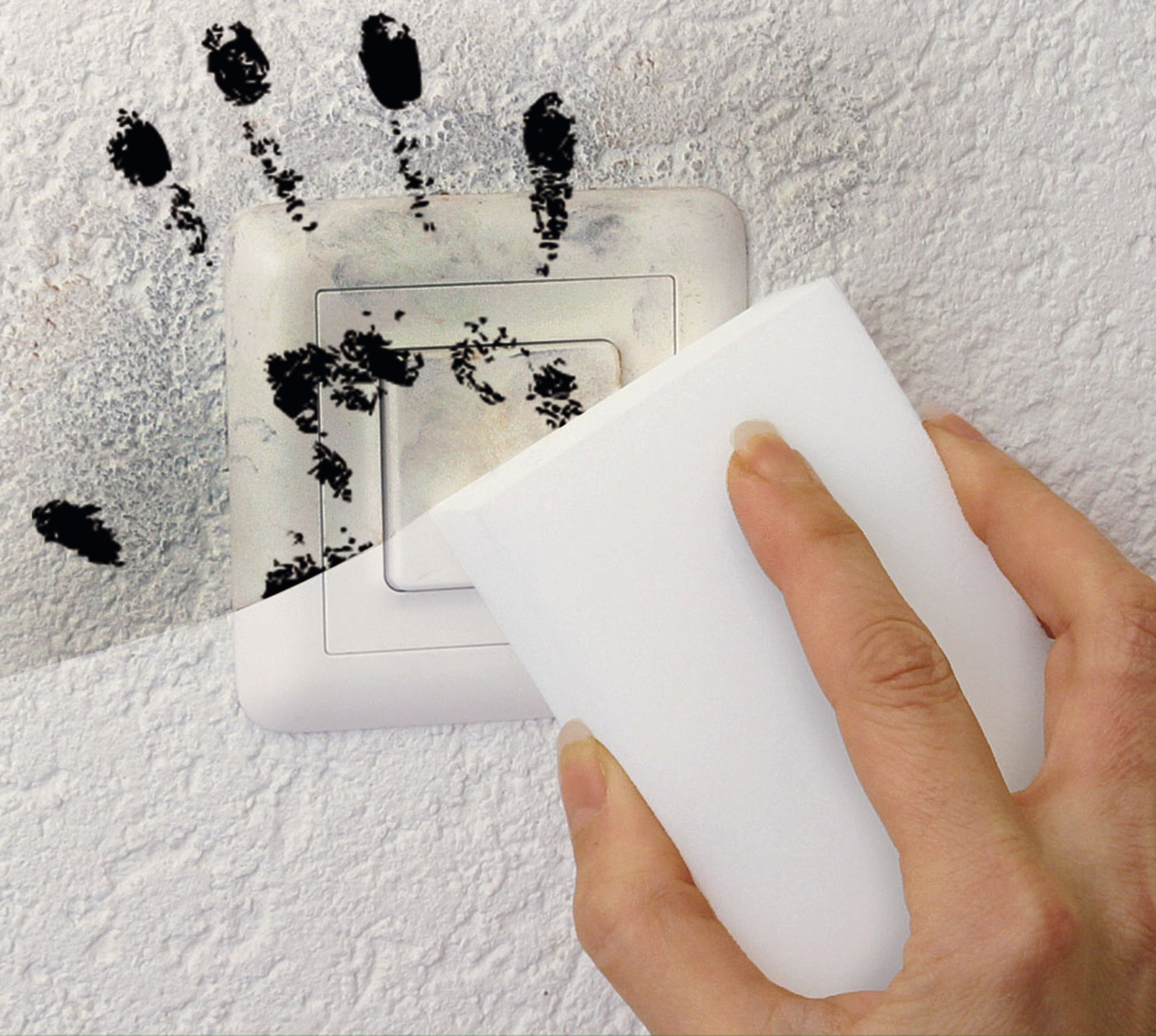 Eine Hand wischt mit dem Scotch-Brite® Magic Pad der 3M Deutschland GmbH schwarze Handabdrücke von einem Lichtschalter auf einer strukturierten weißen Wand.