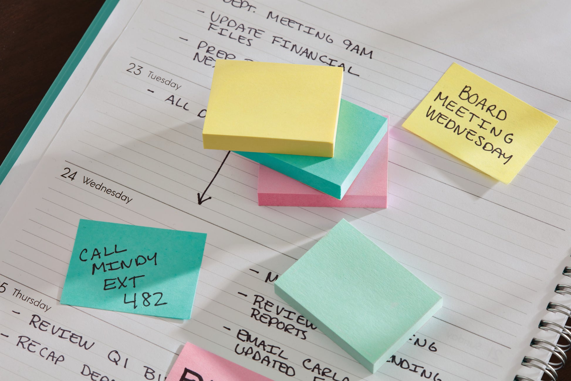 Ein Wochenplaner ist mit mehreren Post-it® Notizen aus der Beachside Collection von 3M Deutschland GmbH (38 mm x 51 mm) versehen, darunter solche mit der Aufschrift "BOARD MEETING WEDNESDAY" und "CALL MINDY EXT 482" sowie einige leere Notizen.