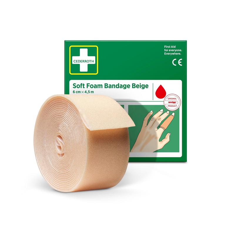 Eine Rolle Cederroth Weichschaumbinde beige 6 cm x 4,5 m von Orkla Wound Care AB steht vor der grün-weißen Schachtel, auf der eine Hand mit bandagiertem Finger und der Name des Produkts abgebildet ist.