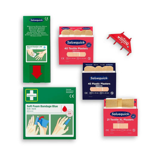 Die Cederroth First Aid Nachfüllpackung für Cederroth Wundpflegespender (Ref 51011006) von Orkla Wound Care AB enthält verschiedene Erste-Hilfe-Materialien, Pflaster, eine weiche Schaumstoffverbandspackung und eine rote Wandhalterung, alles auf weißem Hintergrund.