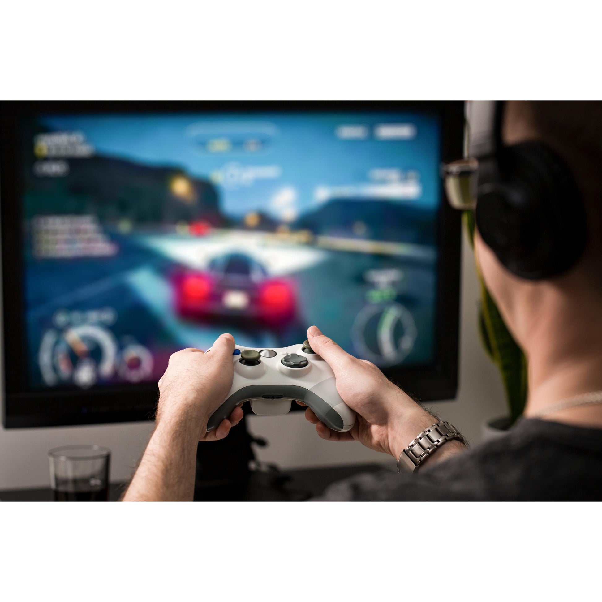 Mit Kopfhörern spielt ein Gamer ein Autorennspiel mit einem roten Sportwagen auf einem großen Monitor. In der Nähe hält das Scotch® Extremium™ INVISIBLE Hochleistungs-Klebeband (20 m x 48 mm) von 3M die Kabel geordnet und aus dem Weg.