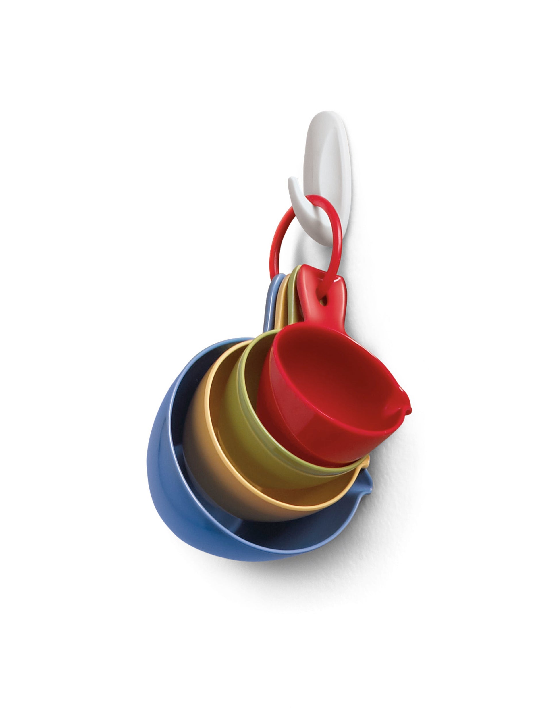 An einem Command™ Small Designer-Haken, 17082 von 3M Deutschland GmbH hängt an einer weißen Wand ein Set aus bunten Plastikmessbechern und -löffeln, die ineinander gesteckt und mit einem roten Ring befestigt sind.