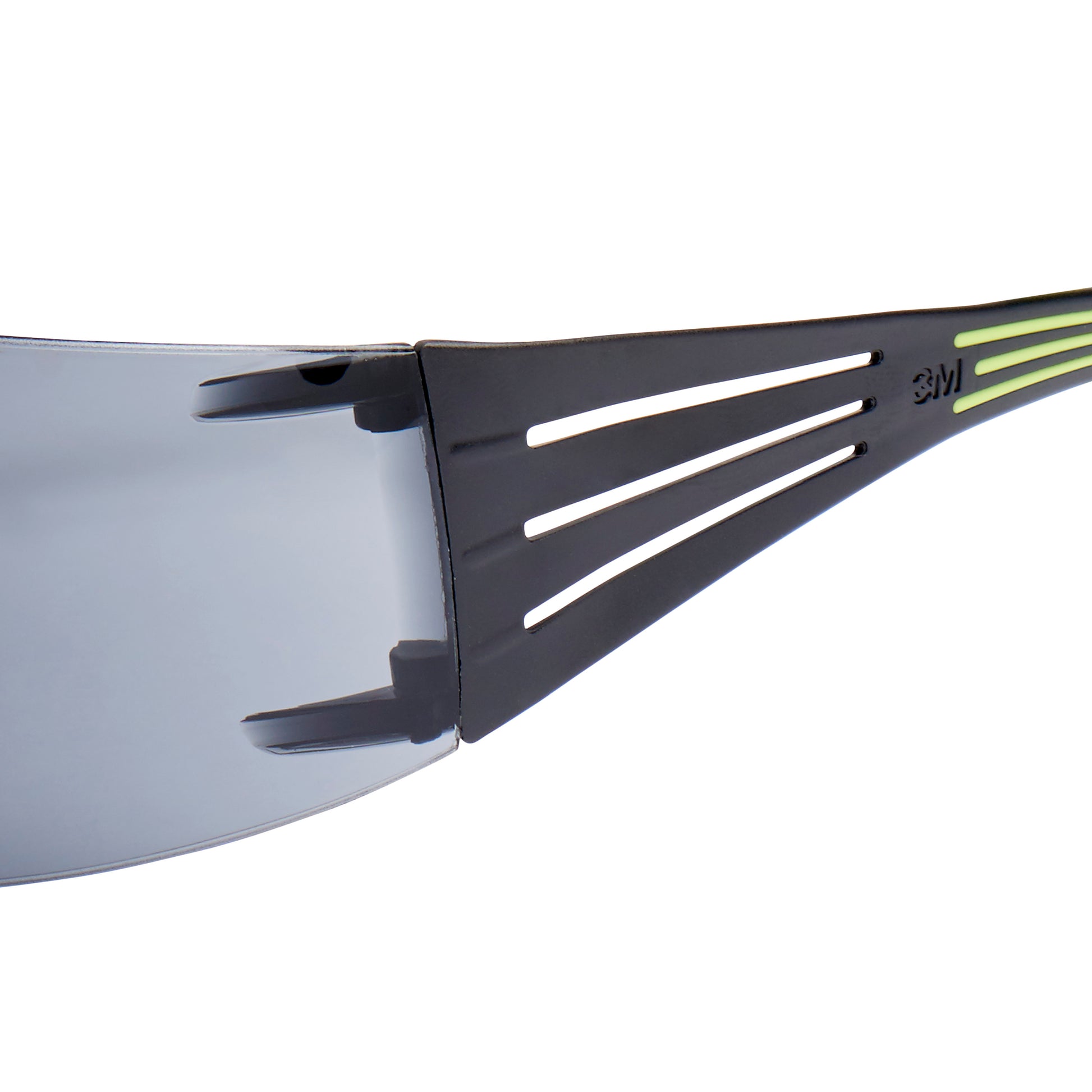 Nahaufnahme der 3M™ SecureFit™ Schutzbrille 400 von 3M Deutschland GmbH, die den schwarzen Rahmen mit dünnen horizontalen Aussparungen, einen kleinen grünen Streifen und eine klare Scheibe zeigt.