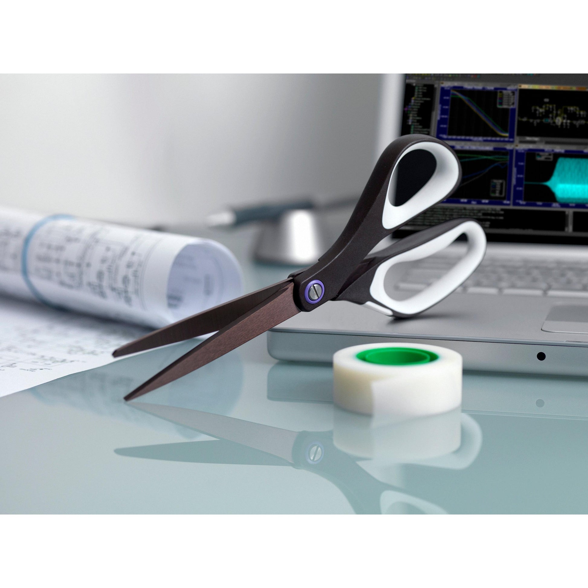 Eine 3M Deutschland GmbH Scotch™ Titanschere, 20 cm, eine Rolle durchsichtiges Klebeband, Dokumente und ein Laptop mit Diagrammen auf dem Bildschirm sind auf einem Glastisch platziert.