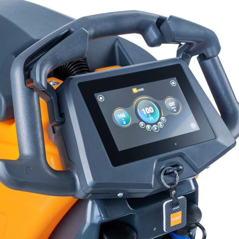 Nahaufnahme eines TASKI IntelliTouch, Interaktives Bedienfeld mit Touchscreen (Diversey Deutschland GmbH & Co. OHG) mit schwarzen Griffen und einem orange-schwarzen Design. Unter dem Bildschirm ist ein Schlüssel mit blauem "TASKI"-Schild angebracht. Verpackung: 1 Stück.