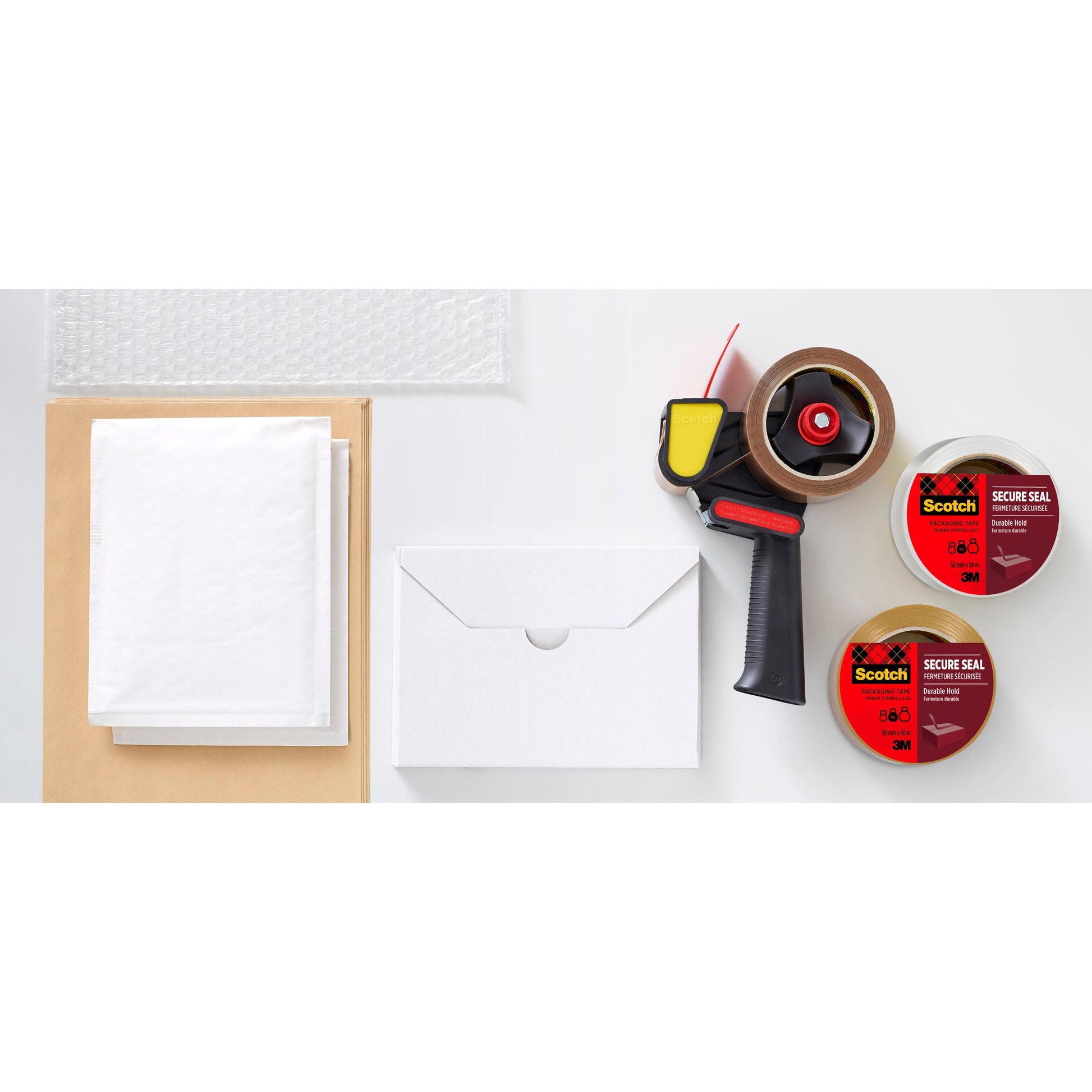 Eine flache Lage mit den wichtigsten Verpackungsmaterialien: Luftpolsterfolie, braune Umschläge, weiße gepolsterte Versandtaschen, ein weißer Karton, ein Klebebandabroller und zwei Rollen 3M Deutschland GmbH Scotch® Verpackungsklebeband für einen sicheren Verschluss (50 mm x 66 m).