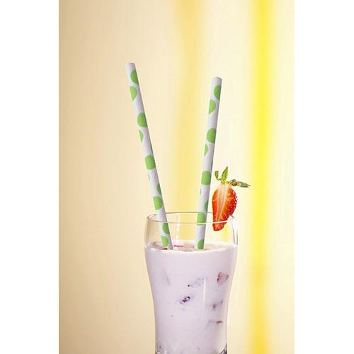 Ein Glas mit cremig-weißem Getränk und Fruchtstückchen wird gekrönt von zwei PAPSTAR 100 Trinkhalmen, Papier Ø 6 mm der PAPSTAR GmbH, mit grünen Punkten und einer Erdbeerscheibe am Rand, vor einem leuchtend gelben Hintergrund.