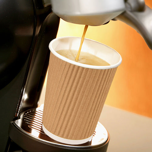 Eine Kaffeemaschine gießt Kaffee in einen Starpak 25 Trinkbecher, einen Pappe „To Go“ Ripple Wall-Becher auf der Metalltropfschale, vor einem warm getönten Hintergrund.