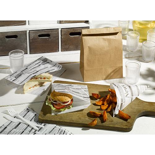 Präsentiert werden Sandwich, Burger und Kartoffelecken auf PAPSTAR 300 Spitztüten „Newsprint“ aus Pergamentpapier (32,5x23x23cm), mit brauner Tüte, Plastikbechern und weißem Besteck – alles von der PAPSTAR GmbH – auf einem weißen Tisch.