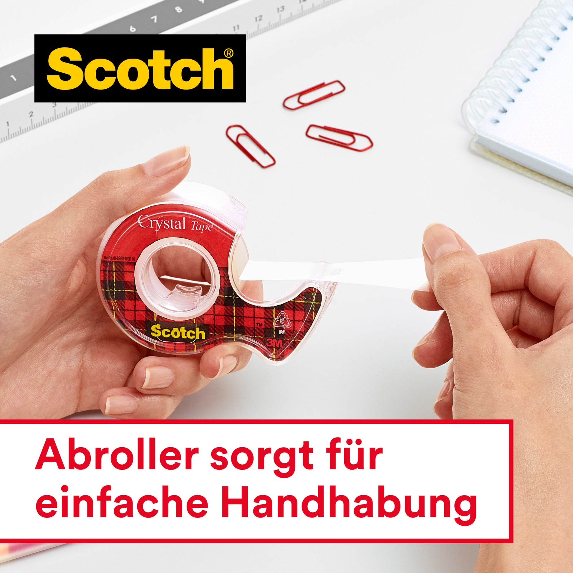 Eine Hand zieht Scotch® Crystal Klebeband (19 mm x 25 m) aus einem Spender. In der Nähe: Lineal, Büroklammern, Spiralnotizblock. Deutscher Text: "Abroller sorgt für einfache Handhabung." Marke: 3M Deutschland GmbH.