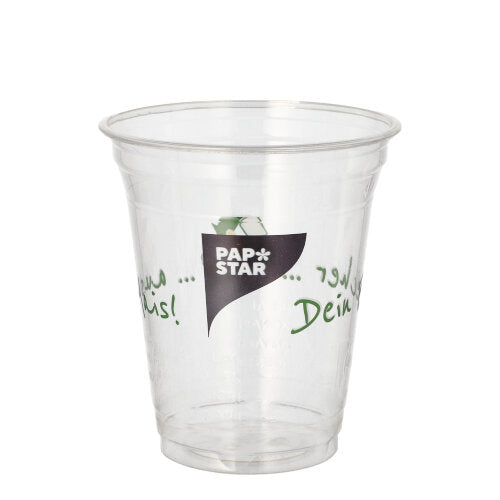Ein durchsichtiger PLA-Becher „PAPSTAR 50 Trinkbecher Becher aus Mais“ der PAPSTAR GmbH mit dem Logo auf der Vorderseite und grünem mehrsprachigem Text an den Seiten ist leer und wird vor einem schlichten weißen Hintergrund präsentiert.