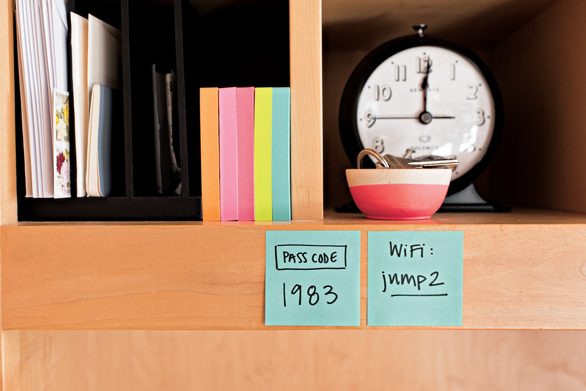 Ein Holzregal mit bunten 3M Post-it® Notes Würfeln (76x76 mm, 450 Blatt), einer Uhr, einer gestreiften Schale mit Schlüsseln und zwei Haftnotizen mit dem Passcode "1983" und dem WiFi-Passwort "jimp2".