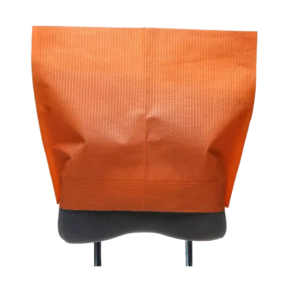 Ein Kopfstützenschoner der AMPri Handelsgesellschaft mbH aus orangefarbenem Seidenpapierstoff ist elegant über die Rückenlehne eines grauen Stuhls drapiert. Seine strukturierte Oberfläche wertet das Design auf, wobei die Stuhlbeine darunter teilweise sichtbar sind. Die offene Oberseite des Bezugs bietet einfachen Zugang und verleiht dieser Zahnarzteinrichtung funktionalen Charme.