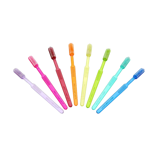 Sieben leuchtende AMPri MED-COMFORT Dental PS Einmal-Zahnbürsten mit Zahnpasta sind ordentlich in einer Reihe angeordnet. Von links nach rechts sind die Farben lila, rosa, rot, orange, gelb, grün und blau. Jede hat ein ähnliches Design mit weichen Borsten, die sich perfekt für die Zahnpflege unterwegs eignen.