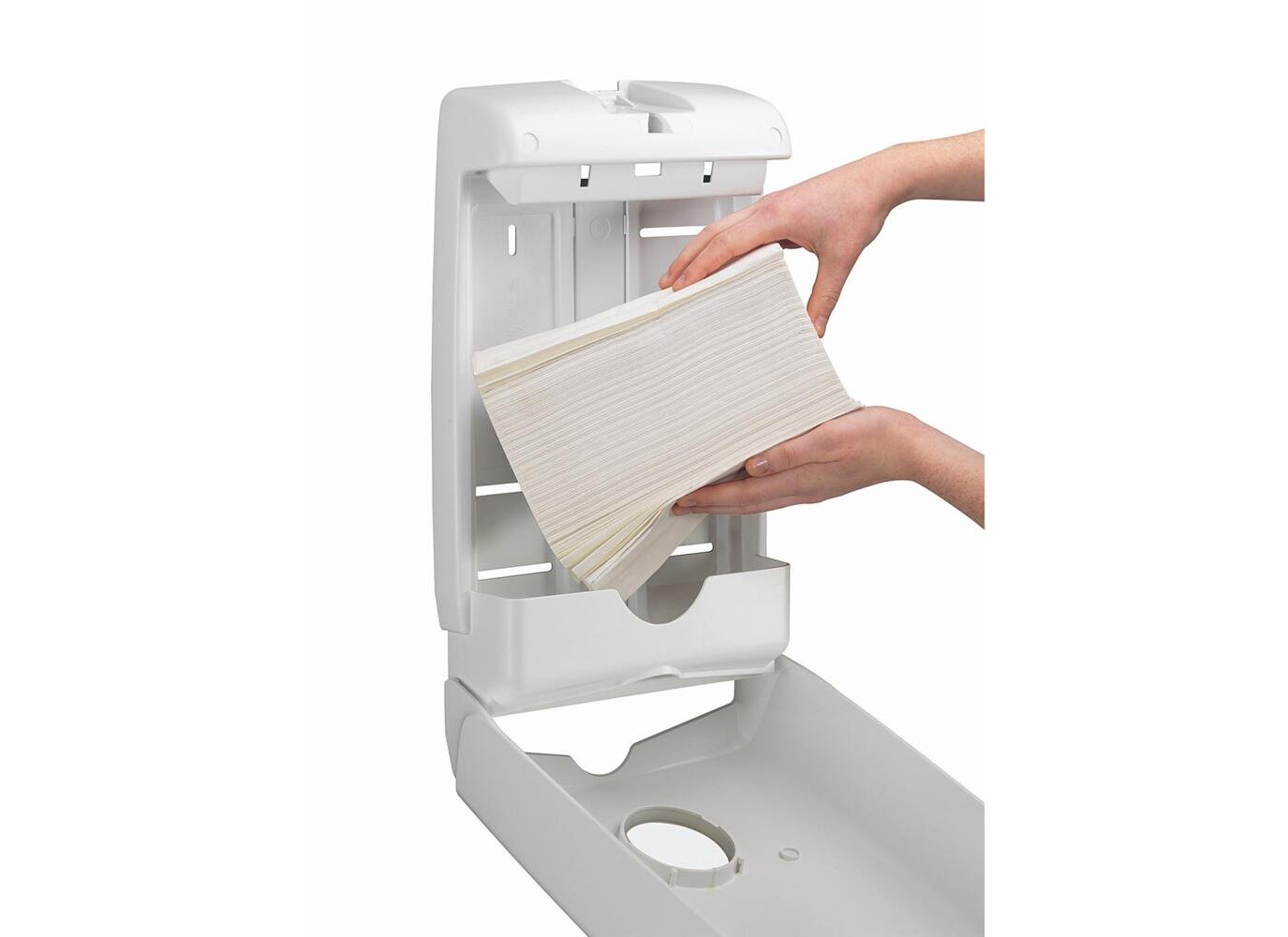 Jemand füllt den an der Wand montierten Aquarius™ Slimfold™ Spender für gefaltete Handtücher (Weiß) von Kimberly-Clark GmbH nach, indem er den Deckel anhebt und einen Stapel gefalteter Handtücher in diesen platzsparenden Spender einlegt.