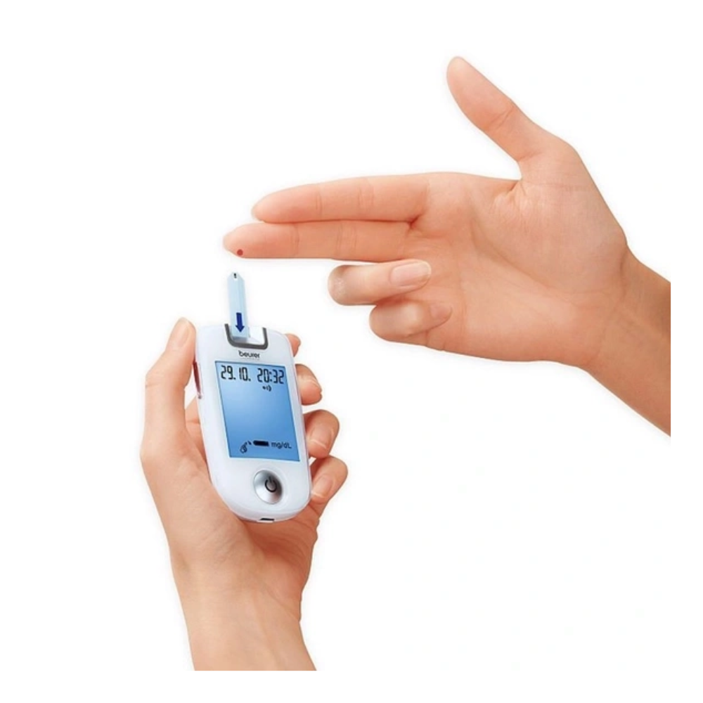 Eine Person hält ein Beurer GL 40 Blutzuckermessgerät in einer Hand, sticht sich in den Finger, um eine Blutprobe zu entnehmen, und hält den Teststreifen bereit, während das Gerät Informationen auf seinem Bildschirm anzeigt – ideal für die Eintragung in Ihr Blutzucker-Tagebuch. Marke: Beurer GmbH.