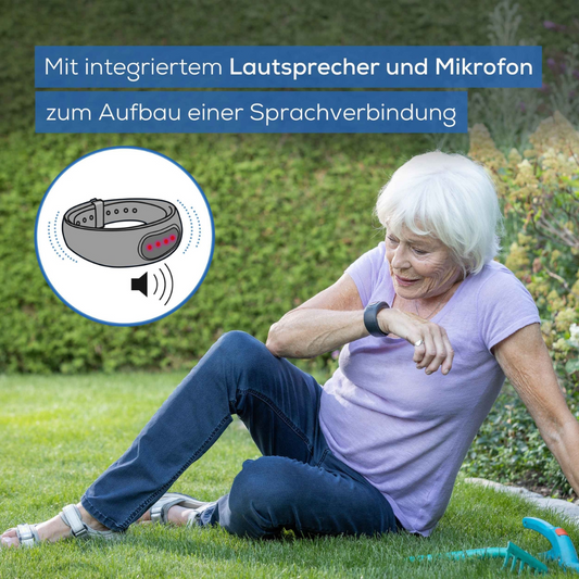 Eine ältere Frau sitzt im Gras und schaut auf ihr Handgelenk, an dem sie ein Beurer Notfallarmband EC 70 SafePlus | Packung (1 Stück) trägt. Das Bild enthält einen deutschen Text, der für ein Gerät mit integriertem Lautsprecher, Mikrofon und Automatischer Sturzerkennung zum Herstellen einer Sprachverbindung in Notfällen wirbt.