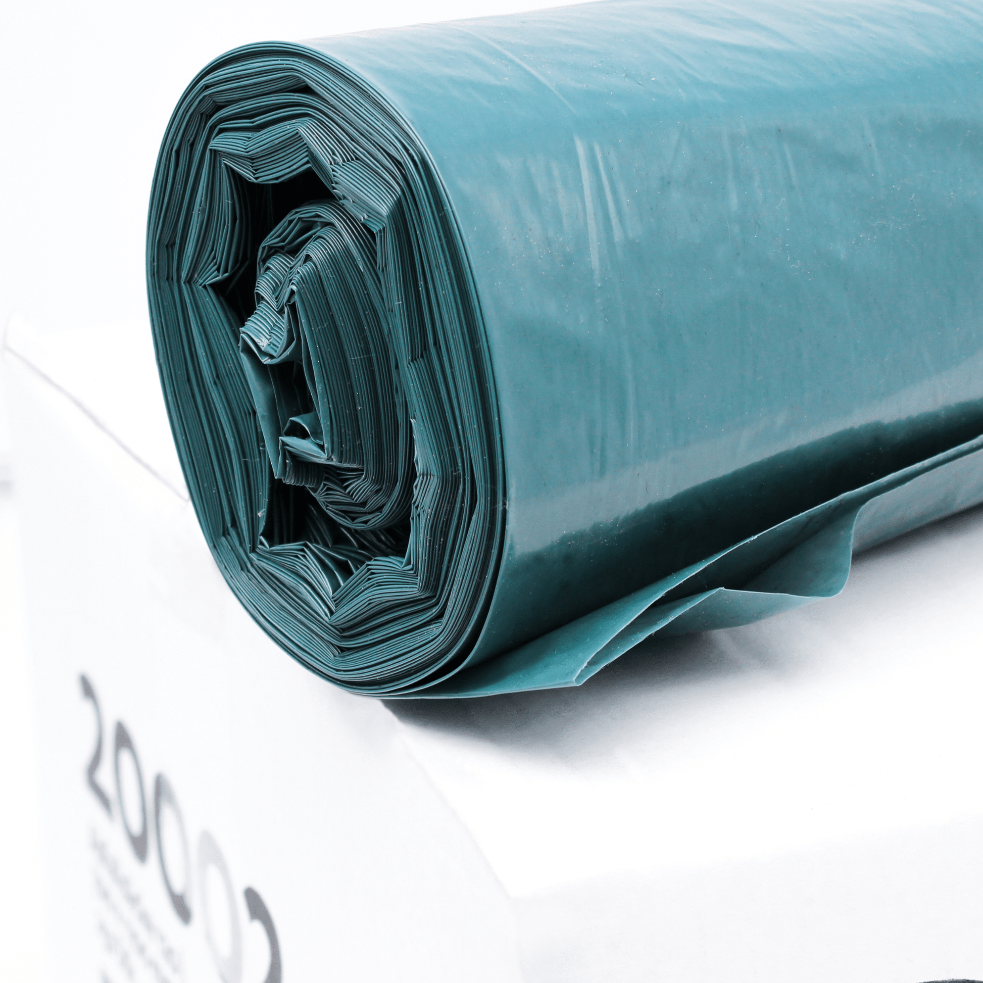 Auf einem weißen Karton liegt eine Großrolle dunkelgrüner DEISS Abfallsäcke 20002, 120 Liter Volumen. Auf der Seite ist in schwarzer Farbe fett die Zahl „2000“ aufgedruckt. Sie steht für die Anzahl der stabilen, leicht entrollten Müllsäcke aus Recycling-PE der EMIL DEISS KG (GmbH + Co.).