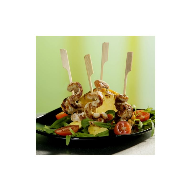 Ein schwarzer Teller mit einem Salat aus Blattgemüse, Kirschtomaten, Gurken, gelbem Käse und vier Garnelen, aufgespießt auf PAPSTAR 250 Fingerfood - Spieße "pure" von PAPSTAR GmbH, senkrecht angeordnet.