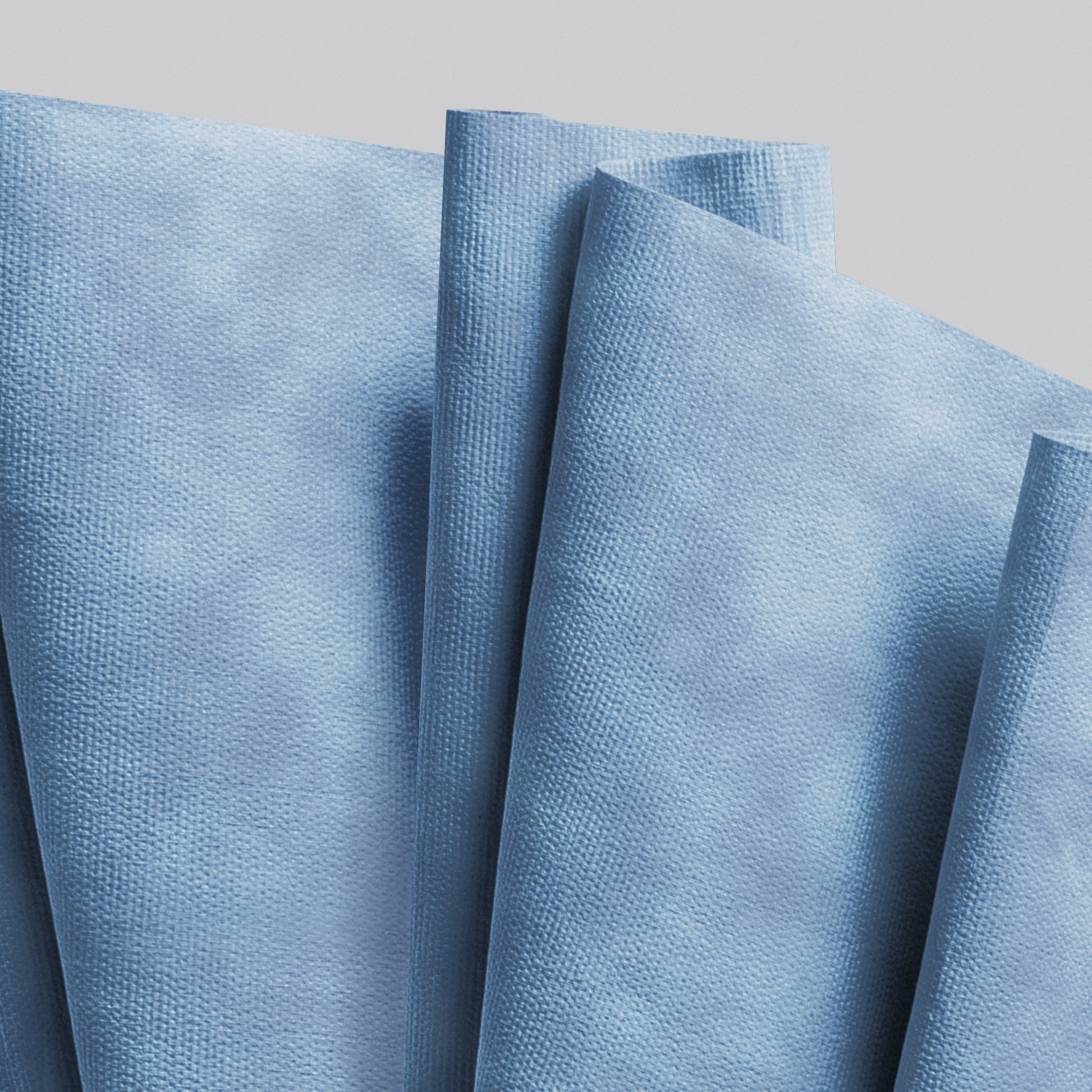 Mehrere blaue WypAll® X90 PowerClean Servietten der Kimberly-Clark GmbH aus der 1 Rolle x 450 Blatt Großrolle sind überlappend vor einem einfarbigen hellen Hintergrund angeordnet.
