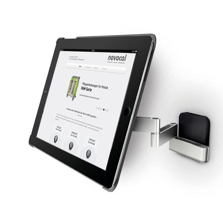 Eine Novocal iPad-Halterung Variante 1 für 7-12 Zoll Tablets, schwenkbar bis zu 180°, ist auf einer weißen Fläche montiert und hält ein Tablet, das die Novocal Website mit Produktinformationen und Navigation anzeigt.