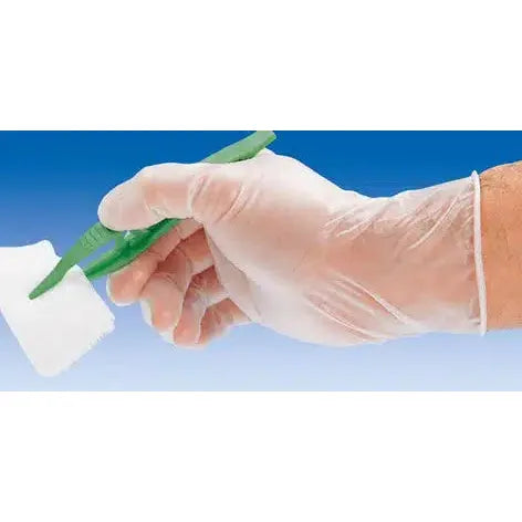 Eine Person mit einem Hartmann Peha-soft® Vinyl Einmalhandschuh, puderfrei, hält eine grüne Plastikpinzette und klemmt ein Stück weiße Gaze vor dem Hintergrund eines blauen Himmels.