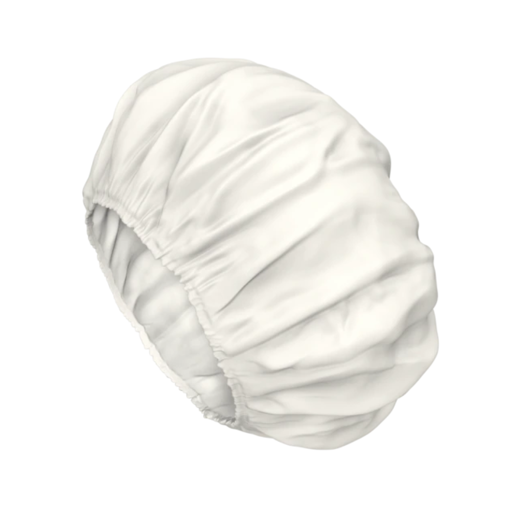 Eine weiße Satinhaube mit gerafften elastischen Kanten zum Schutz der Haare, die an die sanfte Pflege der TENA ProSkin Shampoo Cap Waschhaube erinnert.