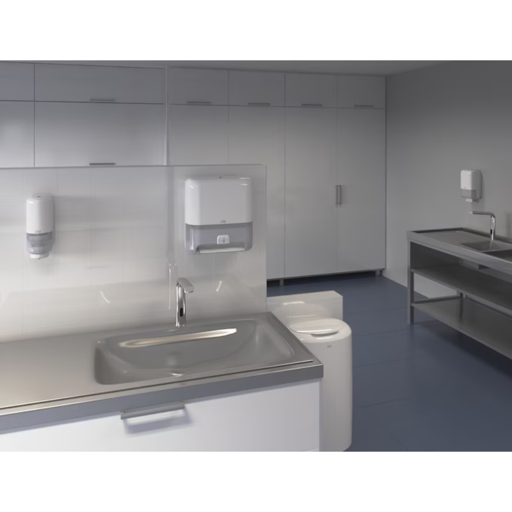 Das Labor besticht durch eine moderne und klare Ästhetik mit weißen Schränken und einem Edelstahlspülbecken. Neben Papierhandtuchspendern ist ein wandmontierter Tork Matic® 551100 Sensorspender für Rollenhandtücher Elevation H1 von TORK – Essity Professional Hygiene Germany GmbH zu sehen. Das Design des Raums ist minimalistisch, mit blauem Bodenbelag und reichlich Stauraum.