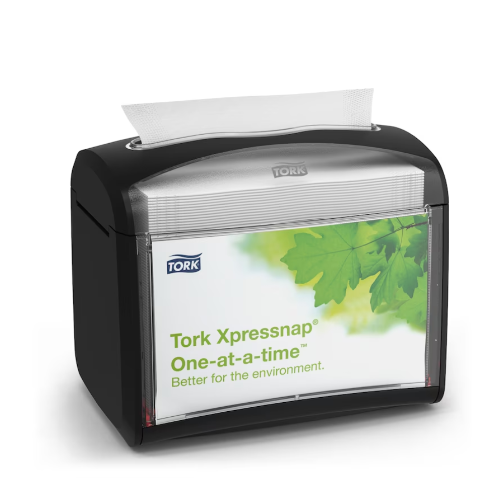 Ein schwarzer Tork Xpressnap® 272611 Tischspender für Servietten, vertrieben von TORK – Essity Professional Hygiene Germany GmbH, wird mit einem Etikett mit grünen Blättern und der Botschaft „Einzeln. Besser für die Umwelt“ präsentiert. Eine einzelne Serviette wird teilweise von oben ausgegeben, um Hygiene und einen effizienten Serviettenverbrauch zu fördern.