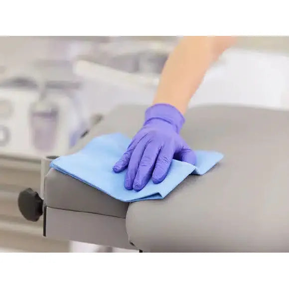 Eine Person mit einem lila Handschuh verbessert ihre Reinigungsleistung, indem sie ein Vileda r-MicronQuick Microfasertuch - 5 Tücher der Vileda GmbH auf einer grauen Oberfläche verwendet.
