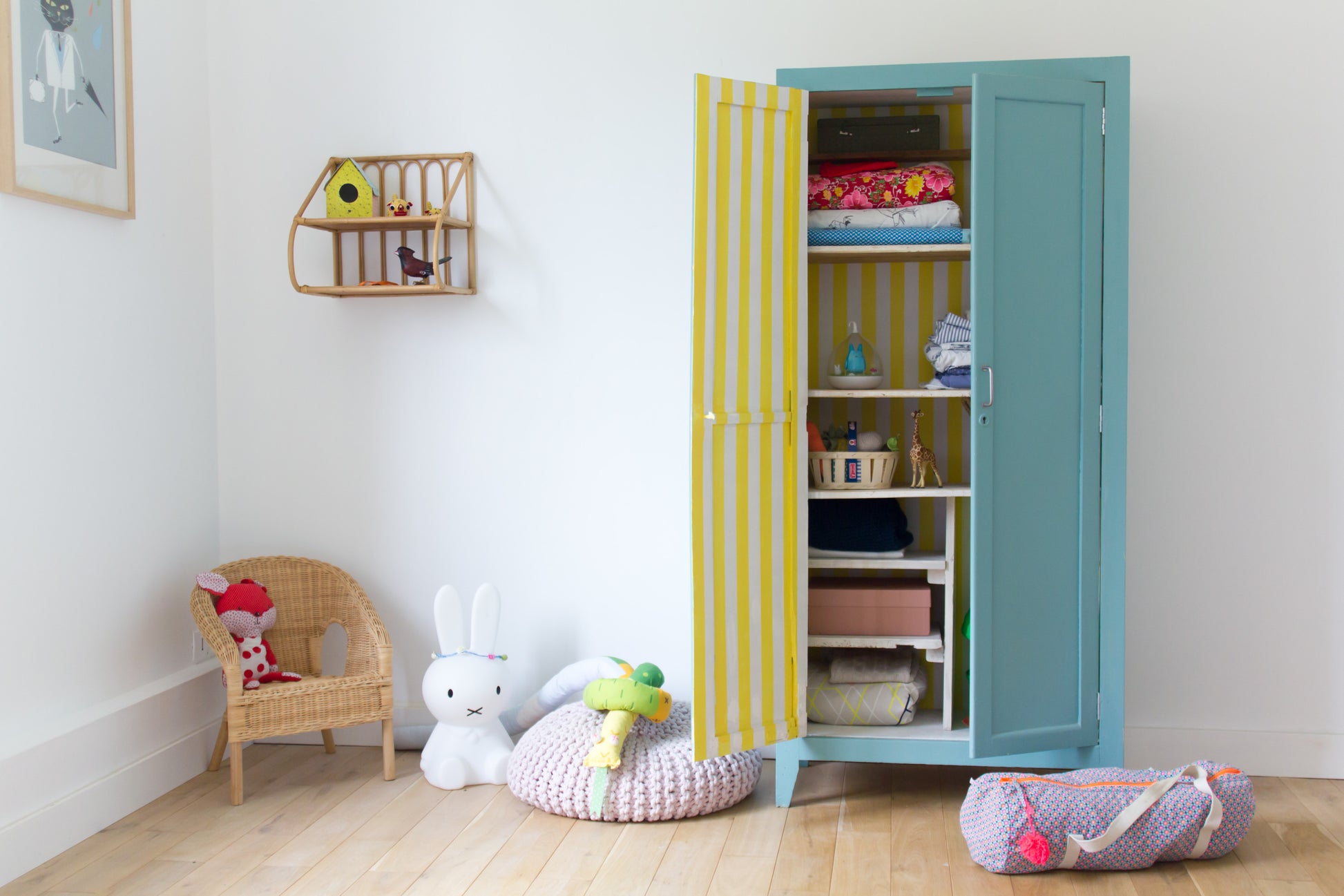 In einem Kinderzimmer mit blauem Kleiderschrank liegt das Scotch® Malerabdeckband für empfindliche Oberflächen von 3M Deutschland GmbH (36 mm x 41 m) neben einem Korbsessel mit Spielzeug, einem Plüschhasen und einem Regal mit kleinen Gegenständen.