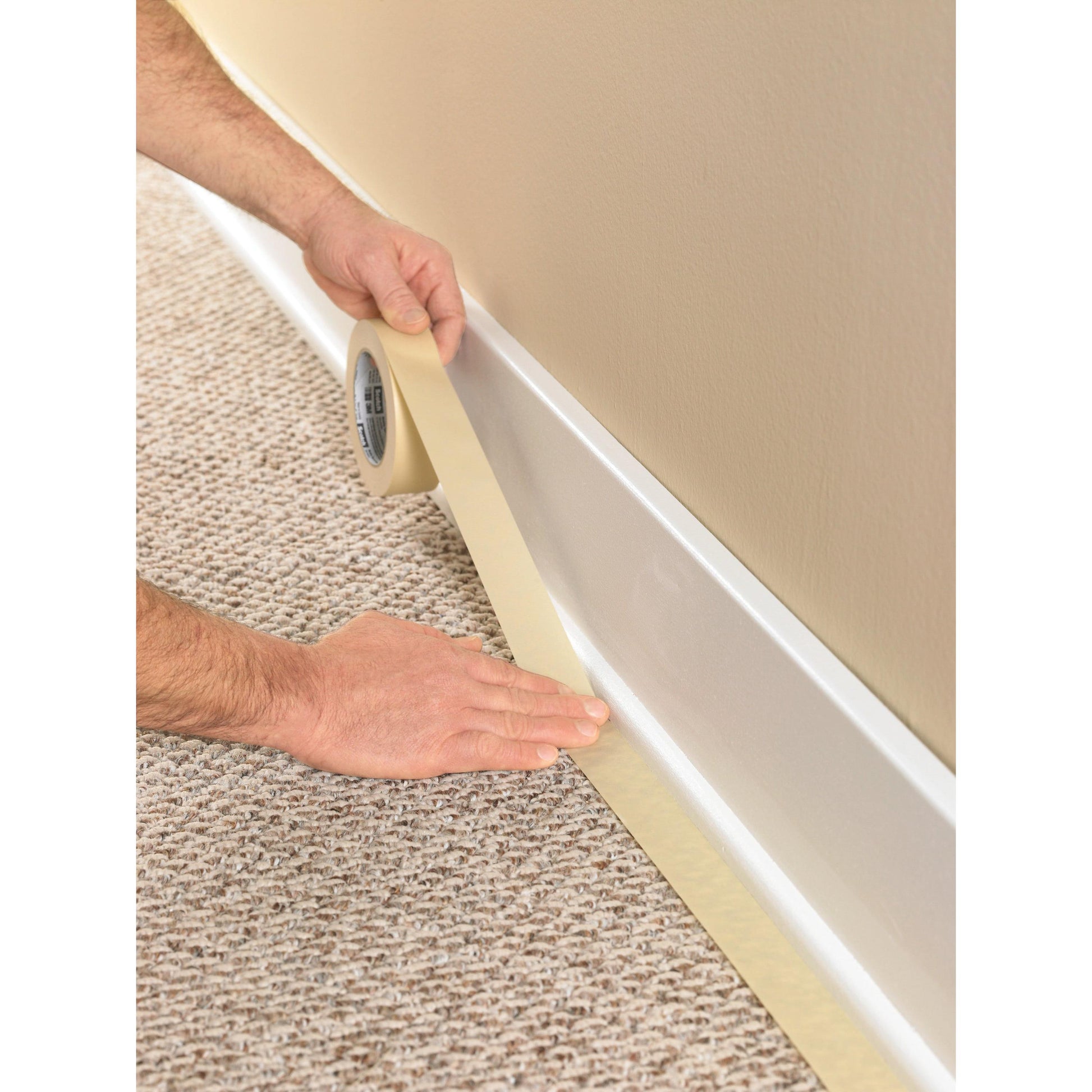 Mit Scotch® Classic Abdeckband (24 mm x 50 m) der 3M Deutschland GmbH wird die Kante einer weißen Sockelleiste neben einem beigen Teppich abgeklebt, um die Fläche für den Anstrich vorzubereiten.