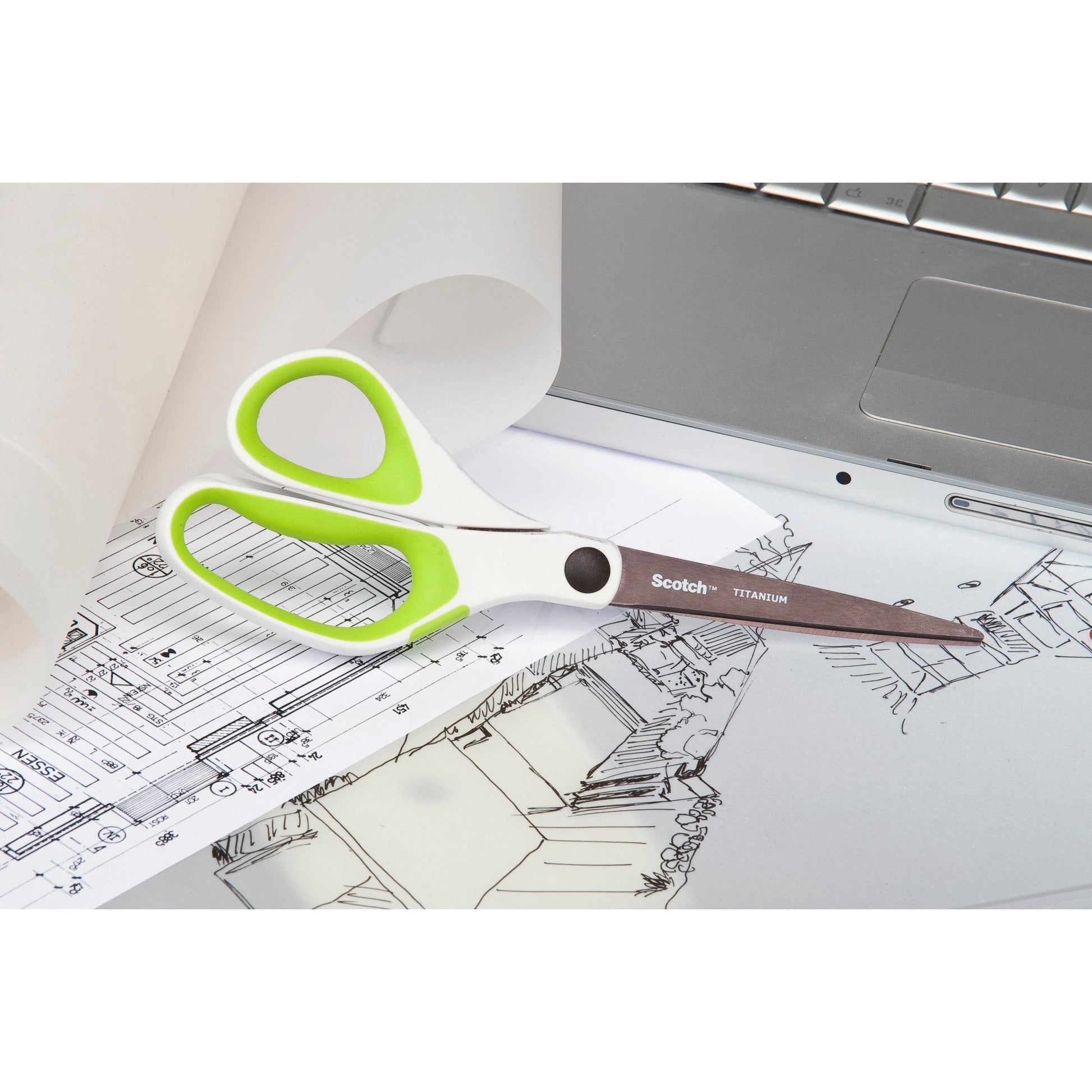Ein Paar Scotch™ Titanschere, 20 cm von 3M Deutschland GmbH, mit weißen und grünen Griffen, ruht auf Architekturzeichnungen neben einem silbernen Laptop und einer Rolle Transparentpapier.
