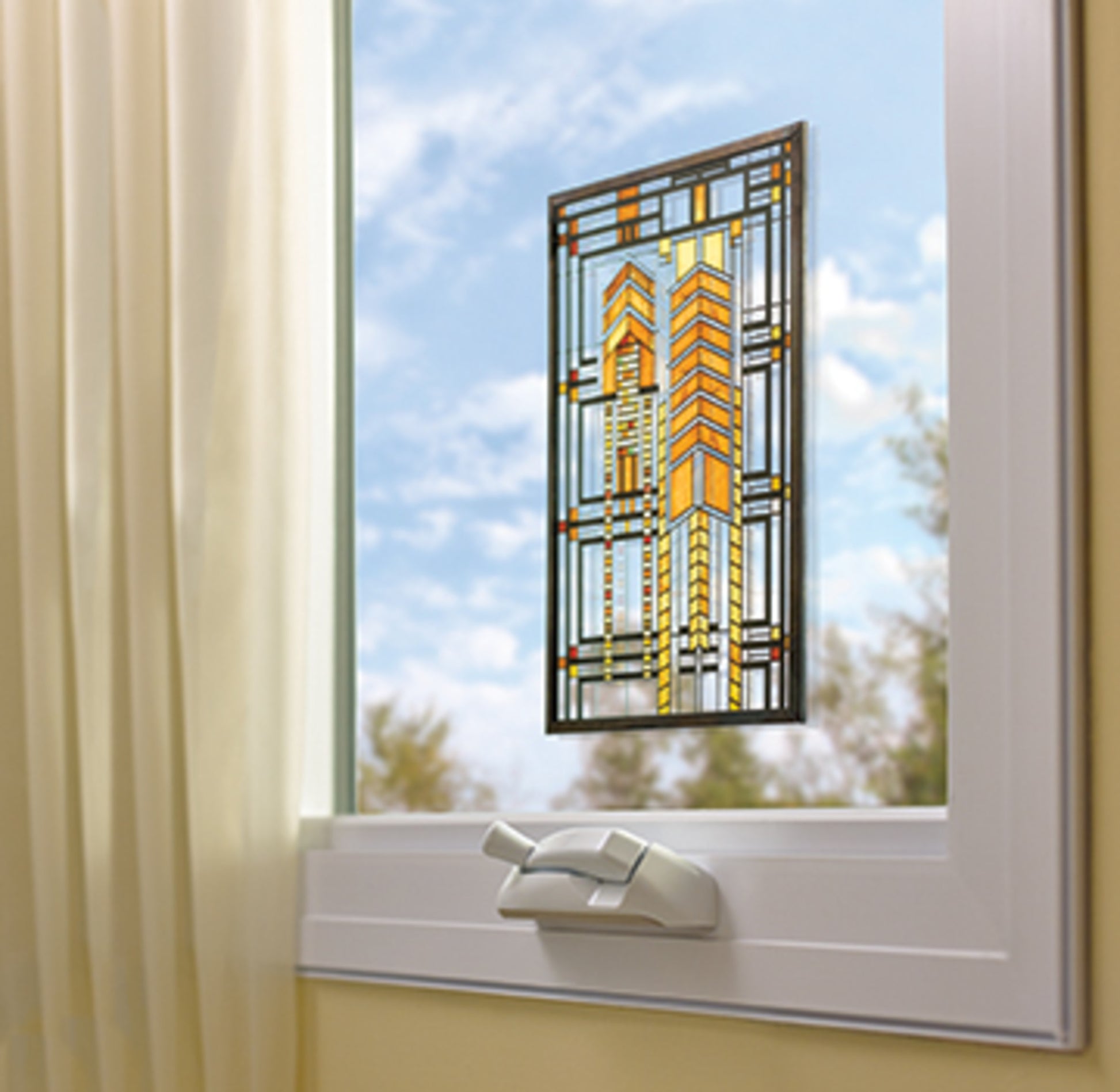 Eine geometrische Glasmalerei wird mit Scotch-FIX™ Transparentes doppelseitiges Montageband 4910C von 3M Deutschland GmbH an einem teilweise geöffneten weiß gerahmten Fenster befestigt. Links hängen helle Vorhänge, draußen sind ein blauer Himmel und Wolken zu sehen.