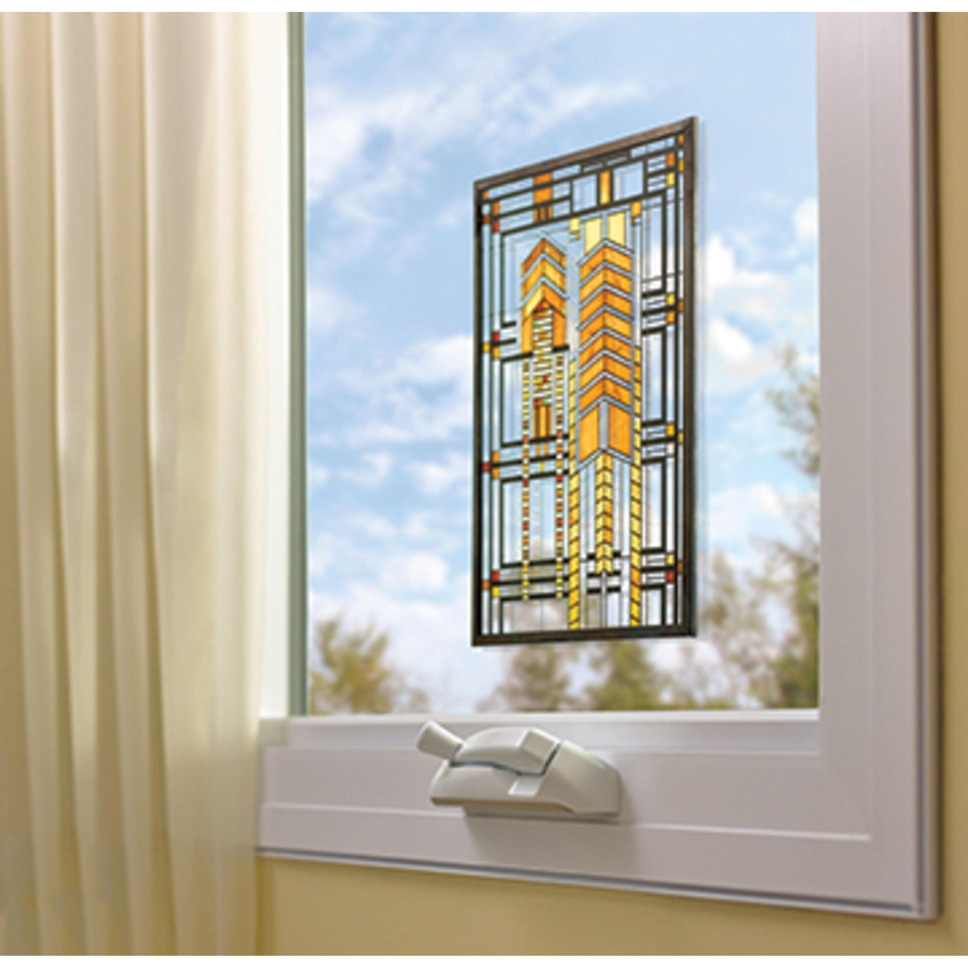 Eine geometrische Glasmalerei wird mit Scotch-FIX™ Transparentes doppelseitiges Montageband 4910C von 3M Deutschland GmbH an einem teilweise geöffneten weiß gerahmten Fenster befestigt. Links hängen helle Vorhänge, draußen sind ein blauer Himmel und Wolken zu sehen.