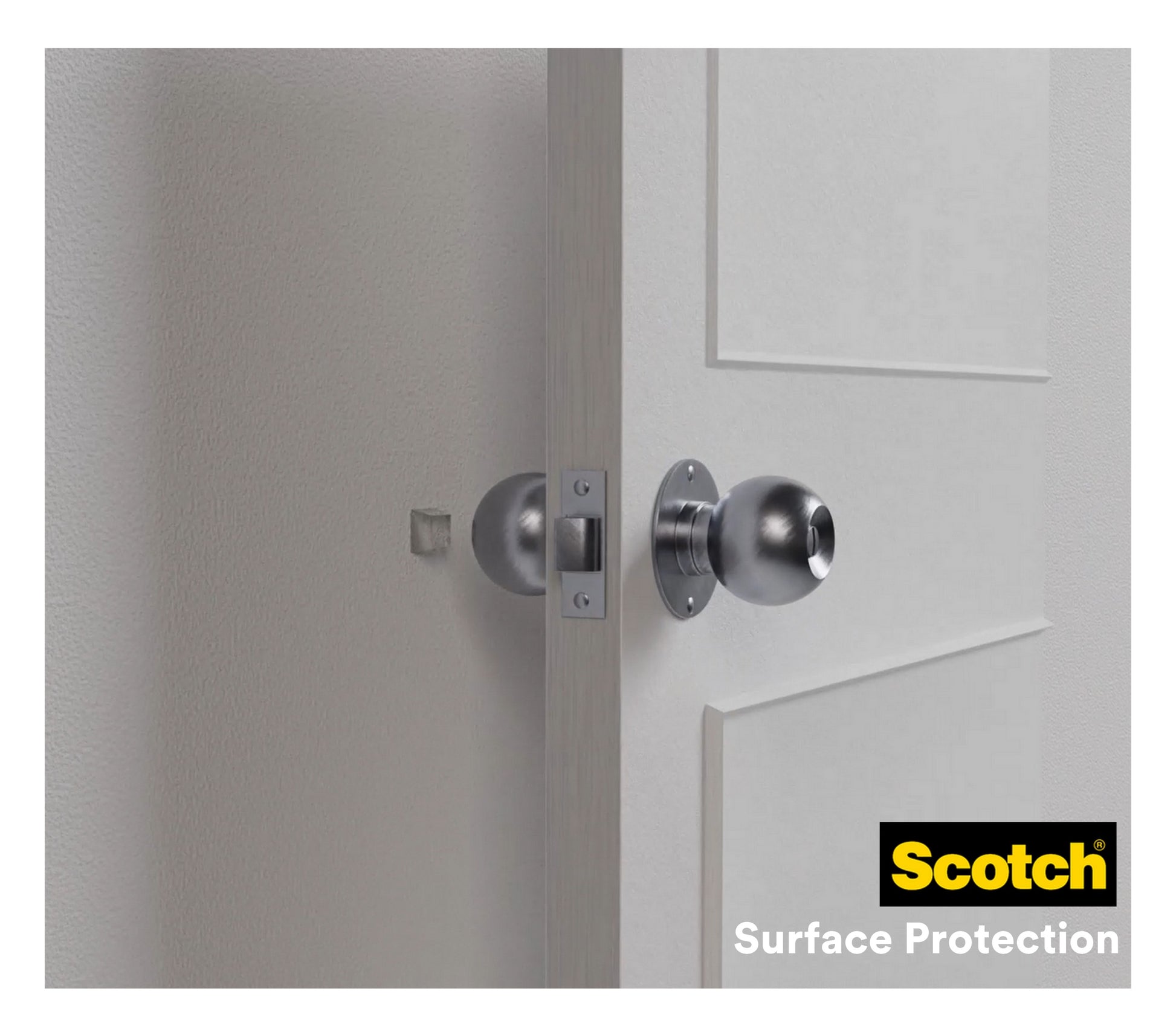 Ein silberner Türknauf an einer weißen Tür berührt fast eine Wand, an der zum Schutz ein transparenter Scotch® Stoßabsorbierende Elastikpuffer für Wände SP91A62 (21 mm x 21 mm, 6/Packung) von 3M Deutschland GmbH angebracht ist.